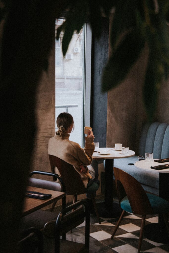 Frau sitzt nachdenklich im Café und überlegt mit Freundin, was sie beim Date falsch gemacht hat